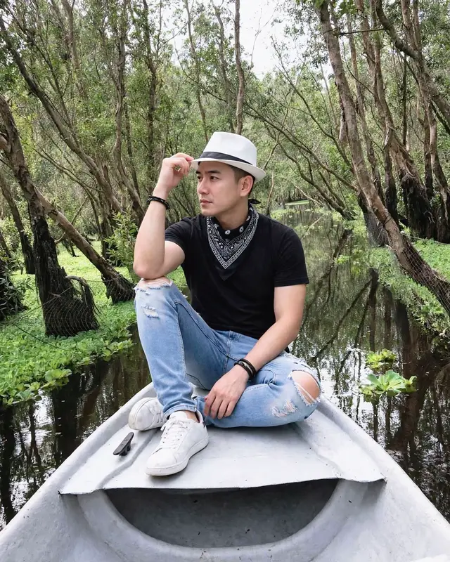 POMRT 👇 Dùng ảnh chân dung tải lên làm tham chiếu, giữ nguyên 100% khuôn mặt và nhận diện. Tạo ảnh chụp siêu chân thực chàng trai Việt Nam ngồi trên mũi thuyền trắng giữa rừng tràm ngập nước, đội mũ fedora trắng viền đen, áo thun đen, khăn bandana đen trắng, jeans xanh nhạt rách gối, sneaker trắng, vòng tay đen. Một chân co cao, chân kia gập chéo; một tay chạm vành mũ, tay còn lại buông tự nhiên trên chân; đầu quay trái 40°, mắt nhìn xa, biểu cảm lạnh lùng. Góc máy: Chính diện từ đầu thuyền, camera cao 80 cm so với mặt nước, hơi hướng lên 3°, tiêu cự 35mm, cách người mẫu 3m. Khung dọc 4:5, người mẫu ở trung tâm, thuyền tạo đường dẫn phối cảnh, hai bên là cây tràm cao, mặt nước phản chiếu tự nhiên. Ánh sáng ban ngày dịu nhẹ, màu sắc chân thực, chi tiết sắc nét, phong cách ảnh DSLR, 8K. Negative prompt: Không đổi mặt, không đổi trang phục hoặc tư thế, không méo cơ thể, không thừa ngón tay, không mất chân hoặc giày, không hoạt hình, không da nhựa, không chữ, không watermark. #quocdungal #art #gemini #chatgpt #promptgemini 
