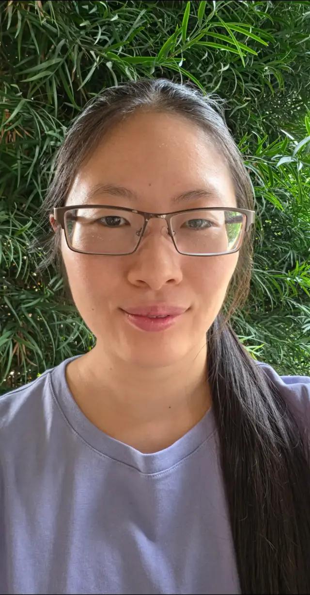 'Cause you do! [ Image: Ang Woon, a smiling light-skinned Chinese-American adult with monolids, long straight pulled-back dark brown hair, rectangular glasses, periwinkle top. Outdoors in front of shrub. ]